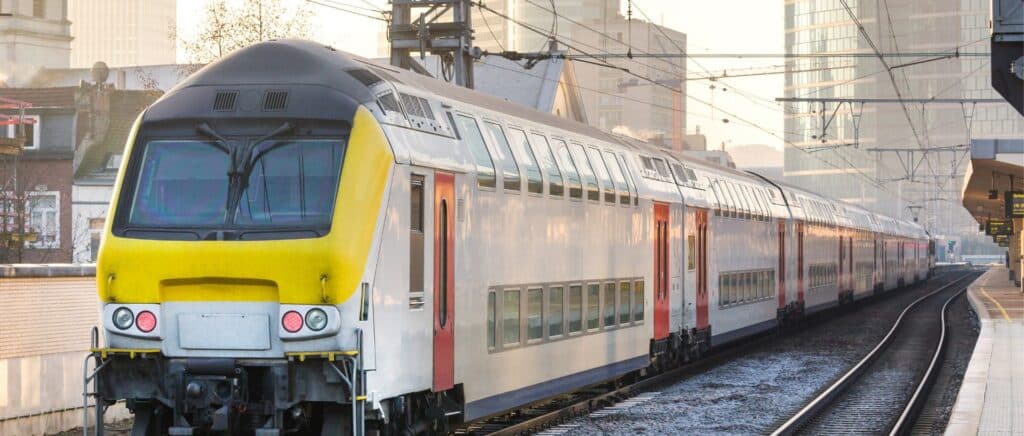 Sleek passenger train at city station, ready for departure amid modern architecture and evening light.