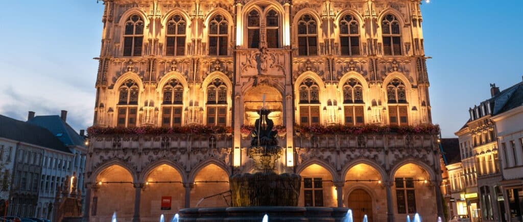 Historisch stadhuis van Oudenaarde in de schemering met gotische architectuur, centrale fontein en culturele charme.